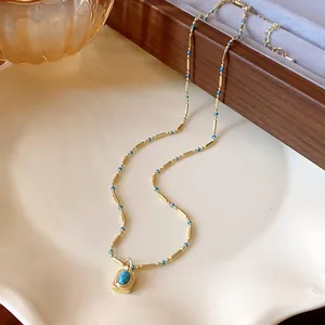 Vue détaillée d'un pendentif turquoise vintage sur une chaîne dorée et perles bleues