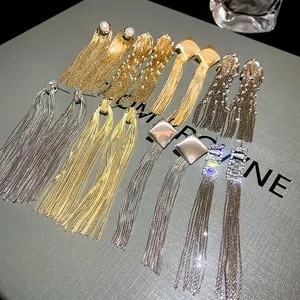 Detail macro view of elegant long metal tassel earrings in gold and silver finishes