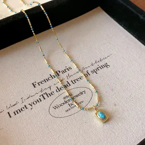 Vue détaillée d'un collier vintage doré avec pendentif turquoise et chaîne à perles.