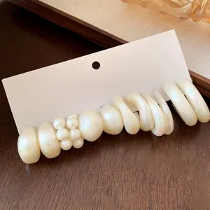Elegant white acrylic and pearl earring set displayed on a minimalist card board