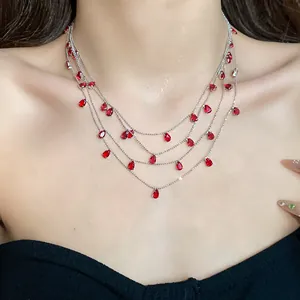 Primer plano de un elegante collar de varias capas con circonitas rojas en forma de gota