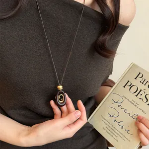 Close-up of retro oval tiger eye resin necklace on a brown sweater background