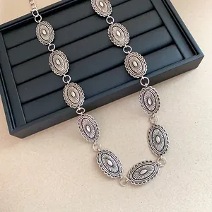 Close-up of vintage engraved oval metal links on a stylish ethnic waist chain belt.