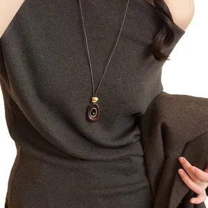 Elegant tiger eye stone resin oval pendant necklace displayed on a dark brown sweater