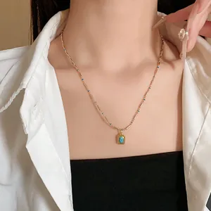 Détail du collier rétro doré avec un pendentif turquoise sur un mannequin