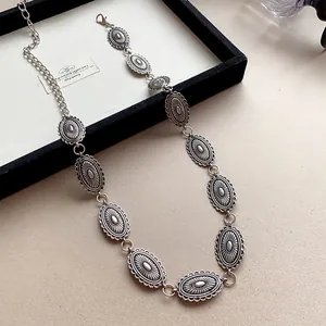 Detail shot of vintage silver metal belt with intricate oval carved links for women.