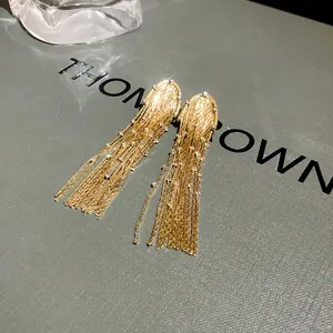 Detailed close-up of elegant long golden fringe earrings with shimmering rhinestones
