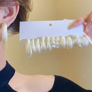 Close-up detail of white acrylic pearl earring set with various hoop and stud designs