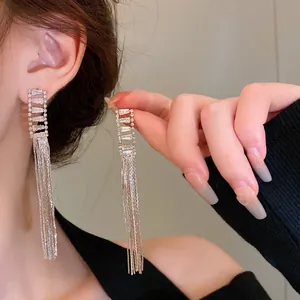 Close-up of elegant long silver tassel earrings with crystal studs worn by a model