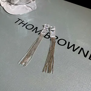 Detailed close-up of long silver metal tassel earrings with sparkling crystal studs