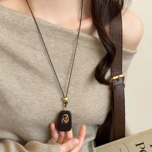 Detailed shot of a vintage tiger eye stone resin pendant necklace on a long brown cord.