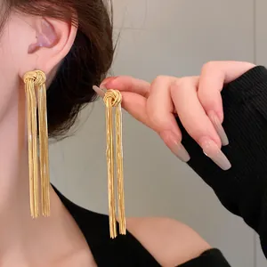 Close-up detail of elegant long golden metal tassel earrings with a knotted design