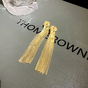 Detail shot of elegant long gold metal tassel knot drop earrings for stylish women.