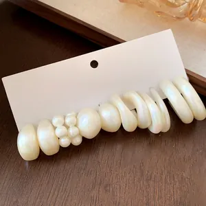 Close-up of elegant acrylic earring set with pearls and geometric shapes on white card
