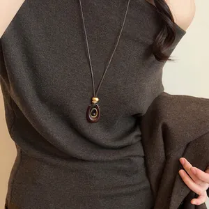 Close-up of a stylish retro oval resin necklace with tiger eye stone on a brown knit sweater