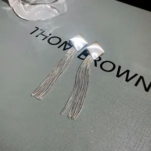 Close-up of elegant silver-tone metal tassel earrings with square stud detail