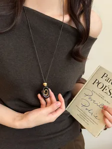 Close-up of a retro resin necklace with tiger eye stone pendant worn by a model