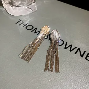 Detailed view of silver metal tassel earrings with rhinestones on a minimalist background.