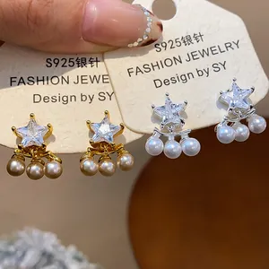 Close-up of elegant star-shaped zircon earrings with delicate pearl pendants and silver needles