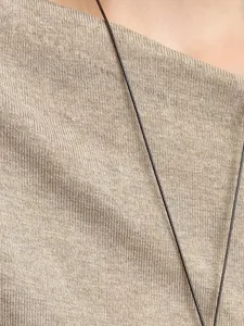 Macro detail of a slim black necklace cord against a beige knit fabric background.