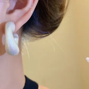 Close-up view of elegant iridescent pearly white acrylic twisted drop earring on model
