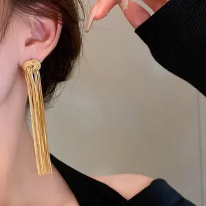 Close-up of elegant gold metal tassel drop earrings with a stylish knot design.