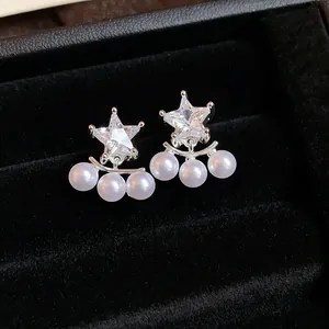 Detail shot of silver star stud earrings with dangling white pearls in a black velvet box.
