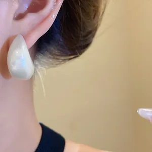 Close-up of elegant acrylic drop earrings with pearlescent finish on model
