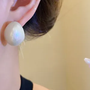 Close-up of minimalist acrylic geometric waterdrop earrings with pearlescent iridescent finish