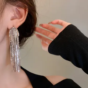 Detail showing a silver metal tassel earring with long elegant draping chains for women.