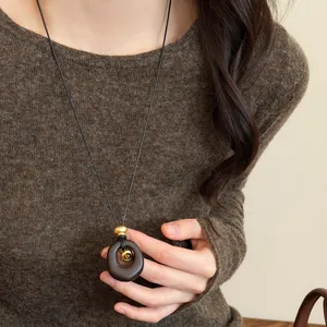 Close-up of vintage resin necklace with tiger eye stone worn on brown sweater.
