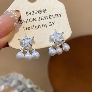Detail of star-shaped zircon earrings with hanging pearls on S925 silver needles