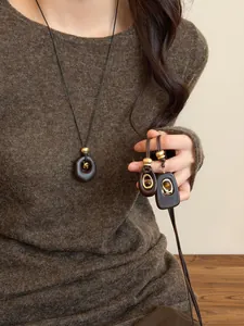 Detailed view of vintage tiger eye stone and resin pendants on long sweater chains