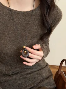 Close-up of a vintage long sweater chain with an oval resin pendant and tiger eye stone.