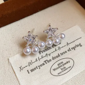 Close-up of star-shaped zircon earrings with delicate pearl accents on display.