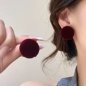 Macro view of vintage burgundy velvet round stud earrings being worn on an ear