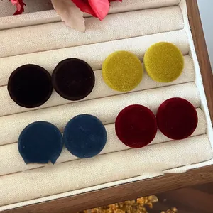 Macro view of vintage round velvet stud earrings in autumn colors displayed in a tray.