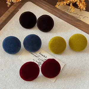 Detailed macro view of retro velvet circular stud earrings in various deep autumn colors