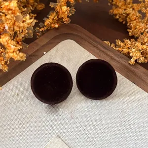 Close-up of vintage round dark brown velvet stud earrings on linen and wood background.