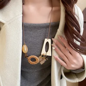 Detail of Bohemian woven rattan and geometric wood bead long necklace on model