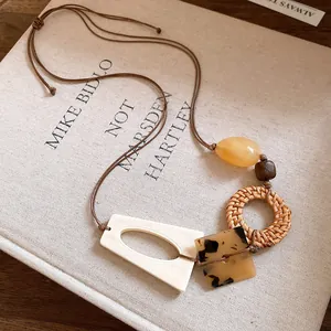 Close-up detail of Bohemian woven rattan and resin geometric pendant necklace