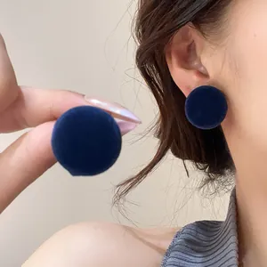 Close-up of dark blue round velvet stud earrings with soft texture detail