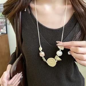 Close-up detail of bohemian handmade necklace with woven rattan and wooden bead pendant