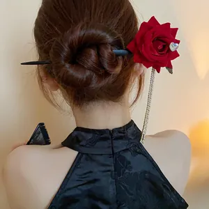 Back view of a vintage red rose hairpin with rhinestone heart and tassel in a hair bun.