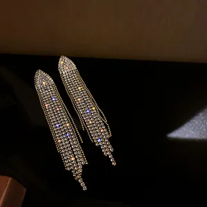 Close-up of shimmering long tassel earrings with multi-colored rhinestone accents