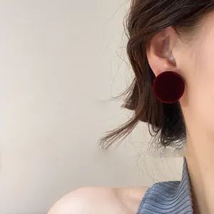 Detailed macro view of vintage red velvet round stud earrings worn on an earlobe