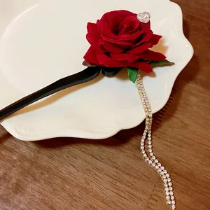 Macro view of a vintage red velvet rose hair stick with elegant sparkling rhinestone tassels.