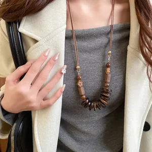 Detail shot of a Bohemian long necklace with layered wooden beads and dark circular discs.