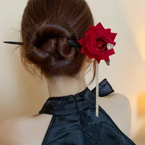 Detailed view of a vintage red rose hairpin with rhinestone heart and long tassels