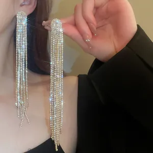 Close-up detail of long silver-plated tassel earrings with shimmering rhinestones.